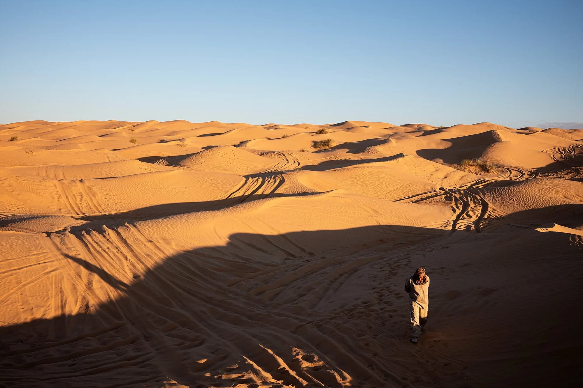 Nomad walking the dunes of the Grand Erg Oriental at golden hour